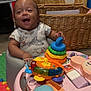 baby, child, smiling, toy, baby_seat, onesie, winnie_the_pooh, colorful, indoor, floor_mat, basket, wooden_wall, play, happy, infant, person, cute, plastic_toy, face, young