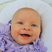 Kayla joined the competition — help win amazing prizes! baby, child, infant, smiling, happy, portrait, face, blue_eyes, lavender, dress, floral, lace, cushion, pillow, nursery, indoor, close_up, sitting, photography, joy