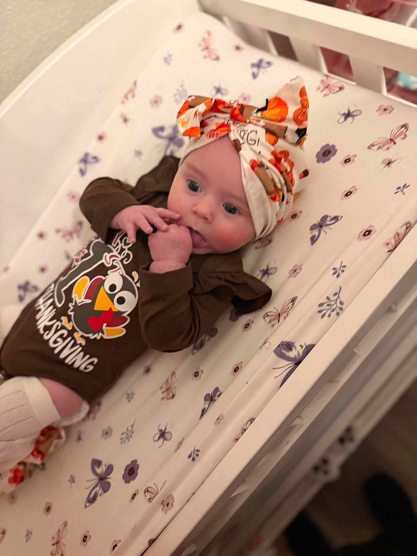 Delylah Rose is registered to the contest to win money with this photo: baby, infant, crib, head_wrap, thanksgiving, brown_clothing, patterned_sheet, butterflies, floral, hand_to_mouth, cute, indoors, sleeping_area, child, person, newborn, socks, pale_skin, soft_lighting, resting