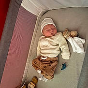 Elyo a rejoint le concours — aidez-le/la à gagner de superbes lots ! baby, sleeping, playpen, pacifier, plush_toy, clothing, hat, striped_socks, brown_pants, white_shirt, soft_toys, indoor, infant, resting, cute, child, blanket, comfort, peaceful, nursery