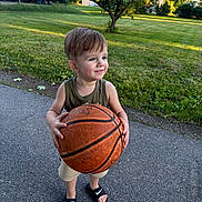 Kylo is registered to the contest to win money with this photo: basketball, child, daylight, grass, greenery, happy, nature, nike, outdoor, pavement, person, playing, recreation, sandals, shorts, smile, summer, tank_top, toddler, tree