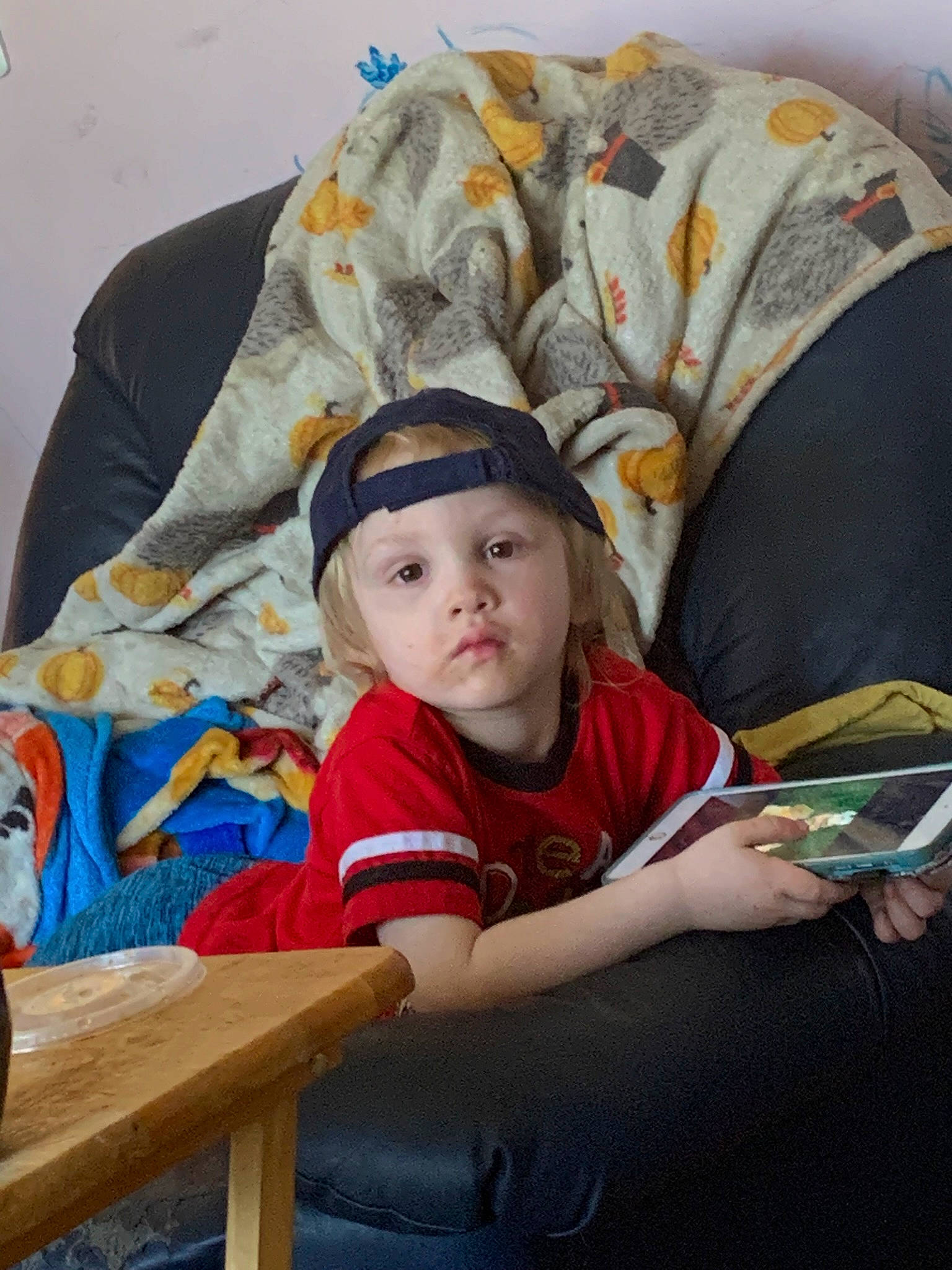 Jasper is registered to the contest to win money with this photo: baby_toddler_clothing, cap, child, comfort, fun, hat, headgear, headwear, lap, leisure, linens, person, room, sitting, sleeve, t_shirt, toddler, vacation, wood