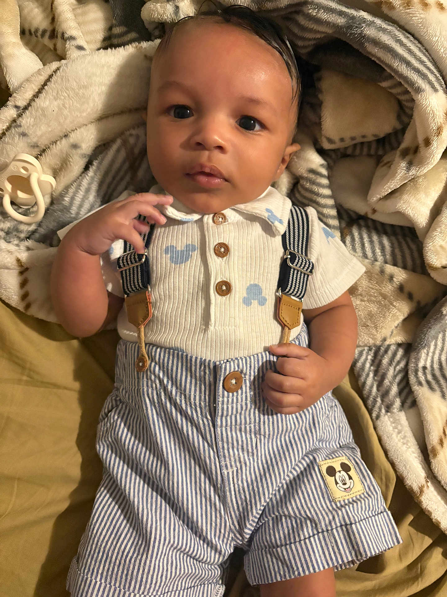Xyion joined the competition — help win amazing prizes! baby, infant, child, face, clothing, striped_shorts, suspenders, mickey_mouse_patch, blanket, pacifier, hand, eyes, head, cute, portrait, sleepwear, soft_texture, indoors, lying_down, curious