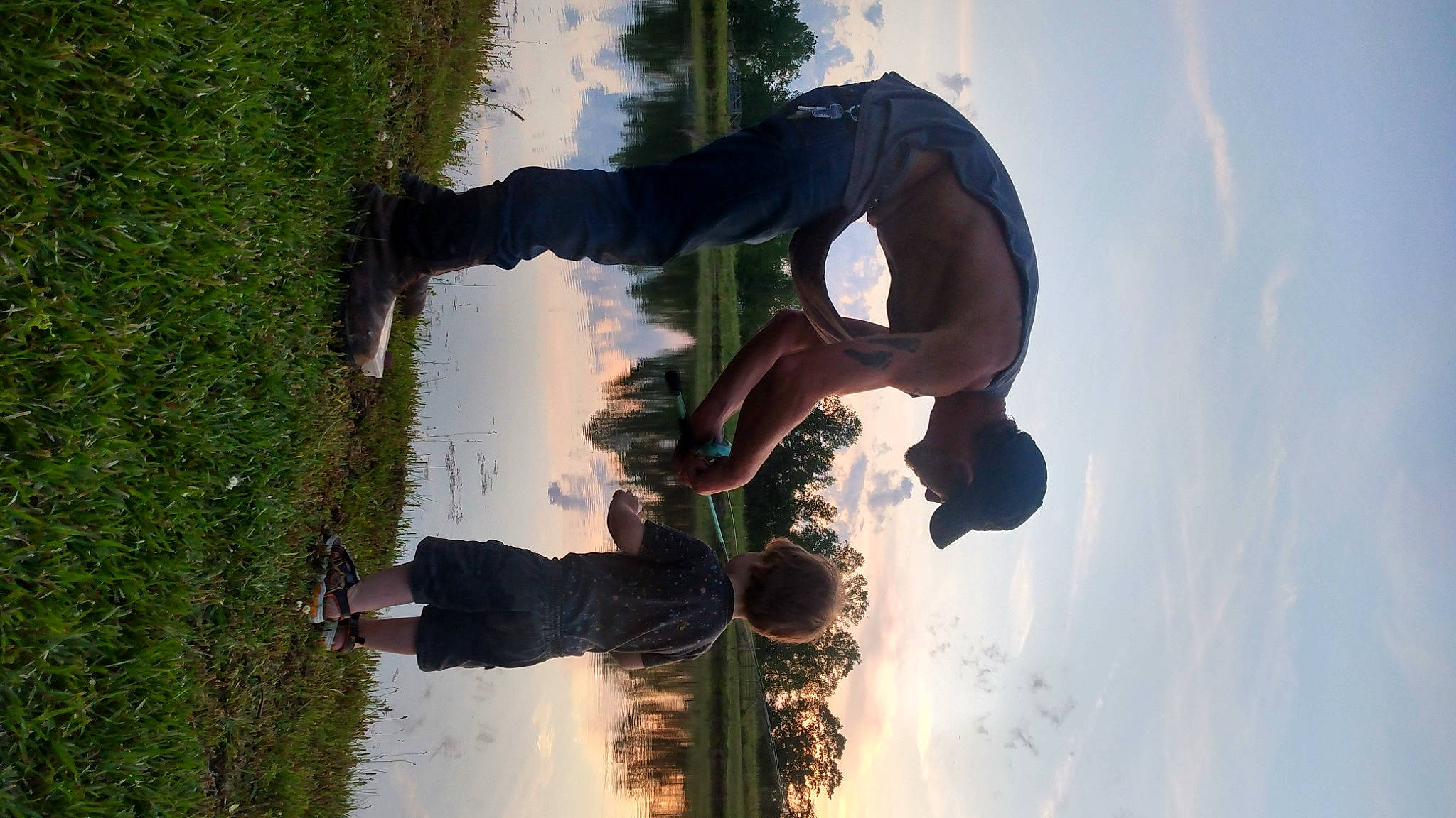 River is registered to the contest to win money with this photo: arm, body_of_water, branch, cloud, fun, gesture, grass, happy, lake, landscape, leisure, people_in_nature, person, plant, recreation, reflection, sky, tints_and_shades, tree, under_exposed