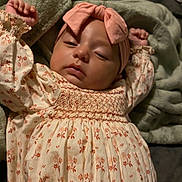Ivory is registered to the contest to win money with this photo: baby, infant, sleepy, headband, bow, blanket, floral_dress, arms_up, indoors, soft_texture, cute, child, portrait, relaxed, cozy, sleepwear, skin, face, young, person