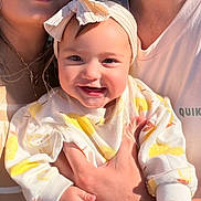Talia is registered to the contest to win money with this photo: baby, child, smiling, headband, bow, hands, clothing, person, adult, family, portrait, closeup, happy, skin, face, sunlight, casual, tshirt, indoor, warm