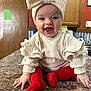 baby, infant, child, bow_headband, headband, smile, laughing, red_socks, ruffled_sleeves, countertop, kitchen, wooden_cabinet, door, portrait, indoor, sitting, happy, mouth_open, eyes, playful