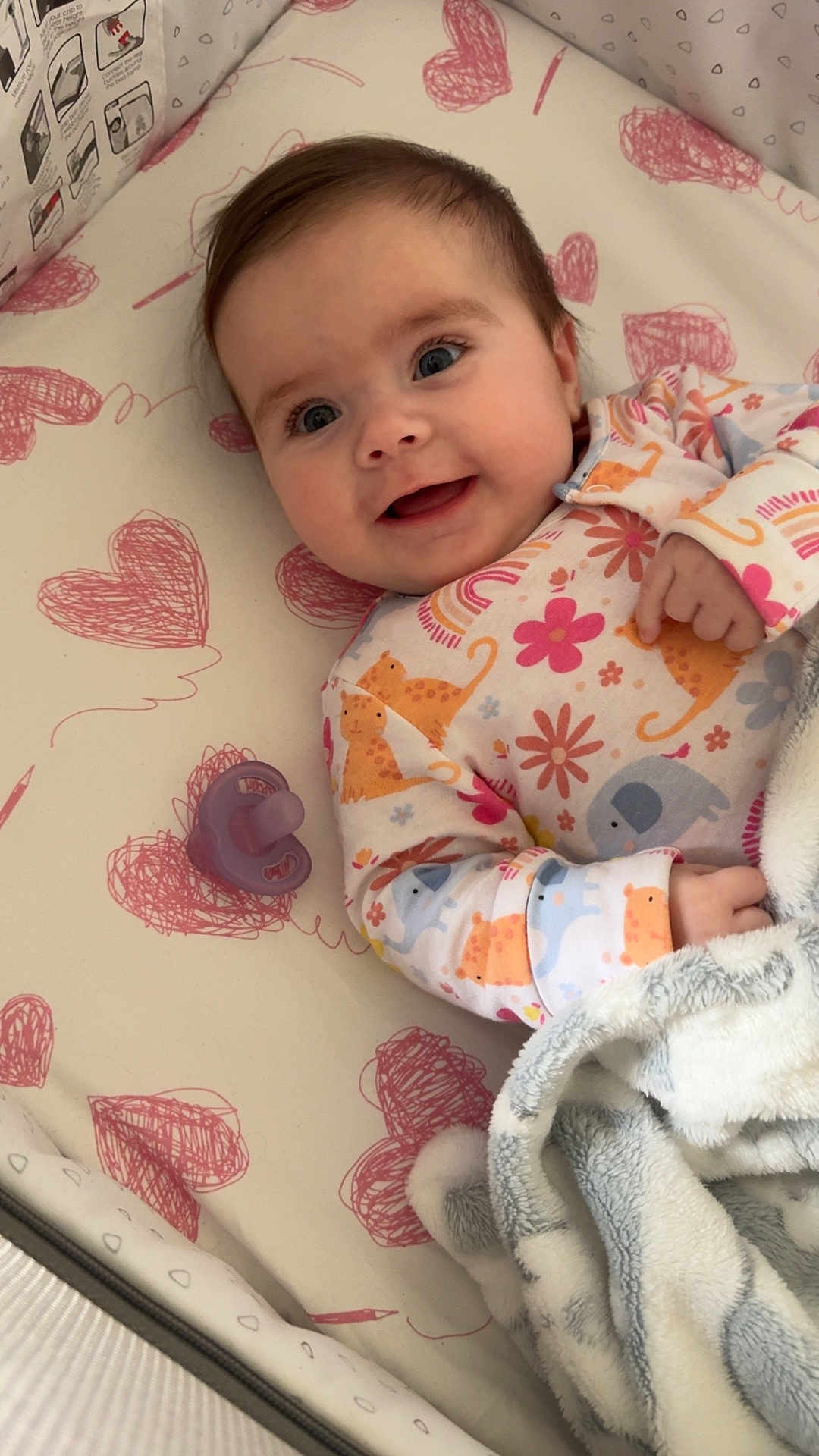 Hallie joined the competition — help win amazing prizes! animal_print, baby, bedding, blanket, child, colorful, crib, cute, face, happy, hearts, indoor, infant, onesie, pacifier, patterned, person, sleeping_area, smile, soft_texture