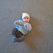 Wesley joined the competition — help win amazing prizes! baby, infant, carpet, hat, sweater, blue, brown_pants, socks, lying_down, indoor, cute, child, person, shadow, texture, knitwear, cozy, expression, playful, floor