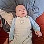 Wesley is registered to the contest to win money with this photo: baby, infant, child, overalls, blue_clothing, face, hand, cushion, blanket, sofa, portrait, indoor, cute, smile, eyes, head, person, skin, light, comfort