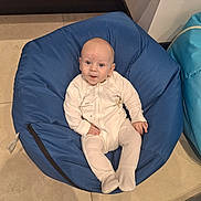 Wesley joined the competition — help win amazing prizes! baby, bean_bag, blue, casual, child, clothing, comfortable, cozy, cute, expression, floor, indoor, infant, looking_up, onesie, person, seat, sitting, tile, young