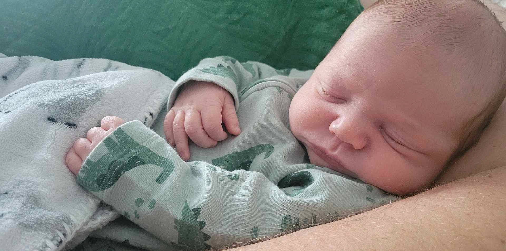 Camden is registered to the contest to win money with this photo: arm, baby, baby_toddler_clothing, cheek, child, comfort, eye, finger, gesture, grass, hand, human_body, linens, mammal, mouth, nail, person, skin, thumb, toddler