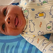 Maison joined the competition — help win amazing prizes! baby, child, smiling, tongue_out, onesie, animal_print, blanket, blue, toy, playmat, mesh, infant, cute, happy, lying_down, colorful, pattern, fabric, indoors, closeup