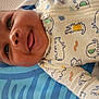 baby, child, smiling, tongue_out, onesie, animal_print, blanket, blue, toy, playmat, mesh, infant, cute, happy, lying_down, colorful, pattern, fabric, indoors, closeup