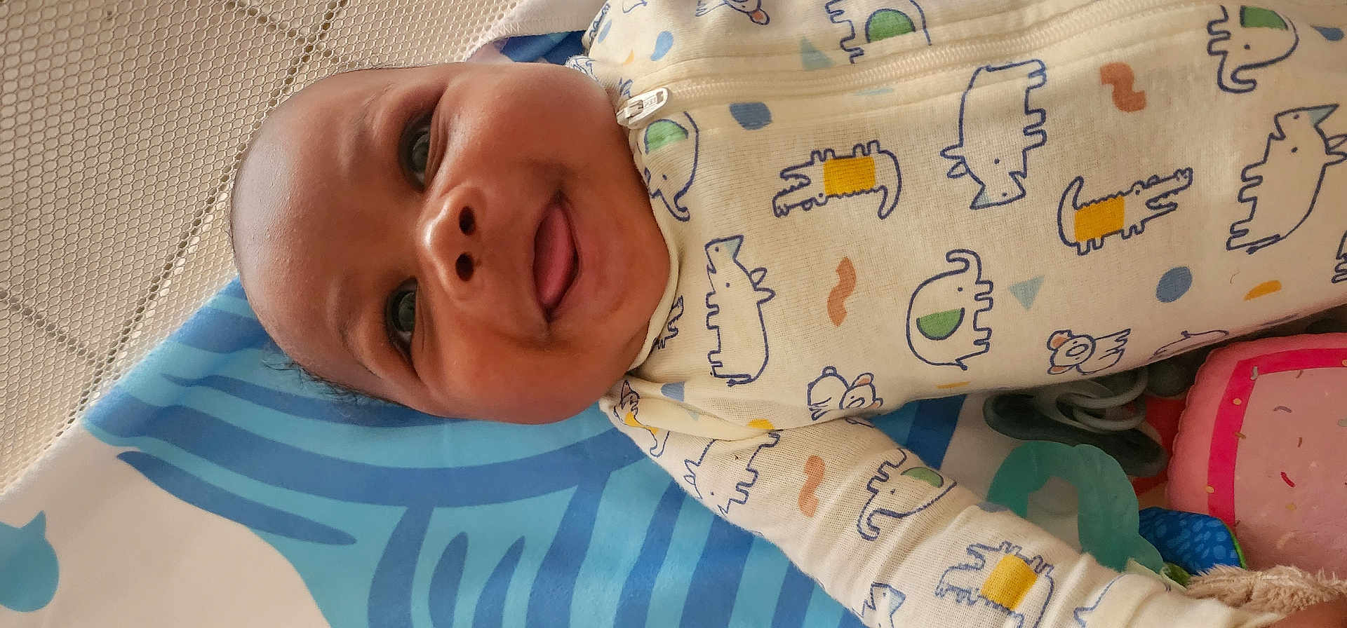 Maison joined the competition — help win amazing prizes! baby, child, smiling, tongue_out, onesie, animal_print, blanket, blue, toy, playmat, mesh, infant, cute, happy, lying_down, colorful, pattern, fabric, indoors, closeup