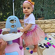 Raïley participe au concours pour gagner de l'argent avec cette photo : toddler, child, pink_tutu, headband, ride_on_toy, play_mat, toys, outdoor, greenery, stone_wall, barefoot, cute, playtime, colorful, happy, girl, summer, daylight, fashion, fun