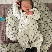 Rafaël a rejoint le concours — aidez-le/la à gagner de superbes lots ! baby, newborn, sleeping, onesie, black_booties, cushion, patterned_cushion, bedspread, quilted_bedspread, pacifier, infant, peaceful, sleep, indoor, child, person, cute, resting, soft, comfortable