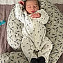 baby, newborn, sleeping, onesie, black_booties, cushion, patterned_cushion, bedspread, quilted_bedspread, pacifier, infant, peaceful, sleep, indoor, child, person, cute, resting, soft, comfortable