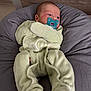 baby, infant, pacifier, onesie, soft_toys, cushion, gray_cushion, green_clothing, newborn, sleepwear, indoor, child, cute, comfort, lying_down, small_child, face, head, skin, resting