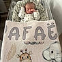 newborn, baby, sleeping, bassinet, blanket, giraffe, elephant, cartoon, sleepwear, indoor, towel, remote_control, wooden_table, cozy, infant, cute, resting, home, child, peaceful