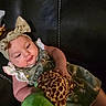 baby, child, comfortable, couch, curious, cute, giraffe_pattern, green_dress, headband, indoors, infant, leather, person, playful, plush_toy, portrait, seated, smile, soft_toy, young_child