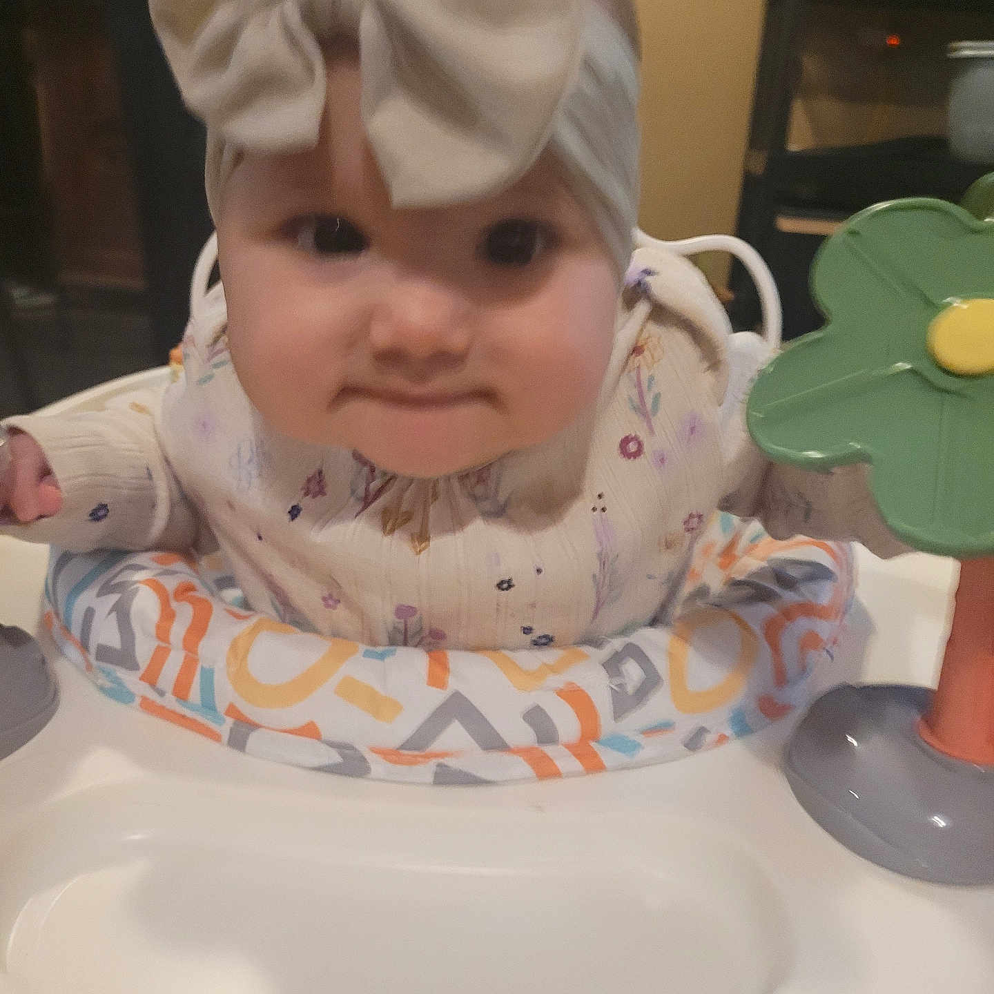 Zoe is registered to the contest to win money with this photo: activity_center, baby, bow, child, colorful, cute, face, flower, hands, headband, indoor, infant, person, play, portrait, smile, sweater, table, toy, young_child