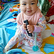 Airalyse is registered to the contest to win money with this photo: baby, bib, blanket, cheeks, colorful, floor, floral_pattern, happy, headband, indoors, infant, onesie, pacifier, playtime, portrait, remote_control, sitting, smiling, soft_toy, toys