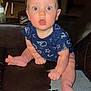 baby, child, infant, dribble, blue_eyes, onesie, sitting, leather_couch, indoor, curious, wide_eyes, clothing, foot, hand, face, expression, young, furniture, home, casual
