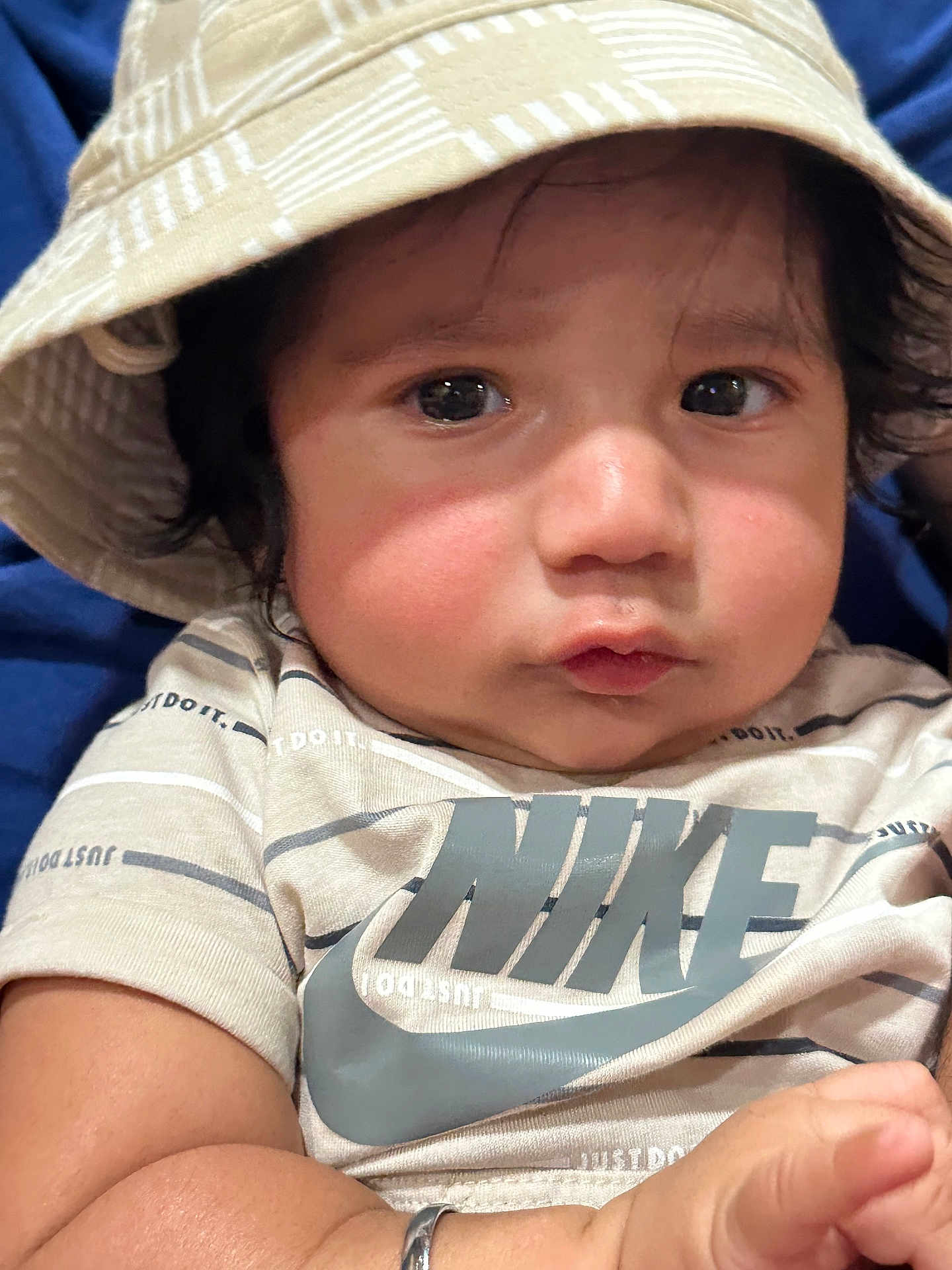 Gurpree is registered to the contest to win money with this photo: baby, child, face, hat, bucket_hat, clothing, nike, tshirt, arm, skin, cute, portrait, closeup, indoor, person, expression, young, infant, curious, wearing