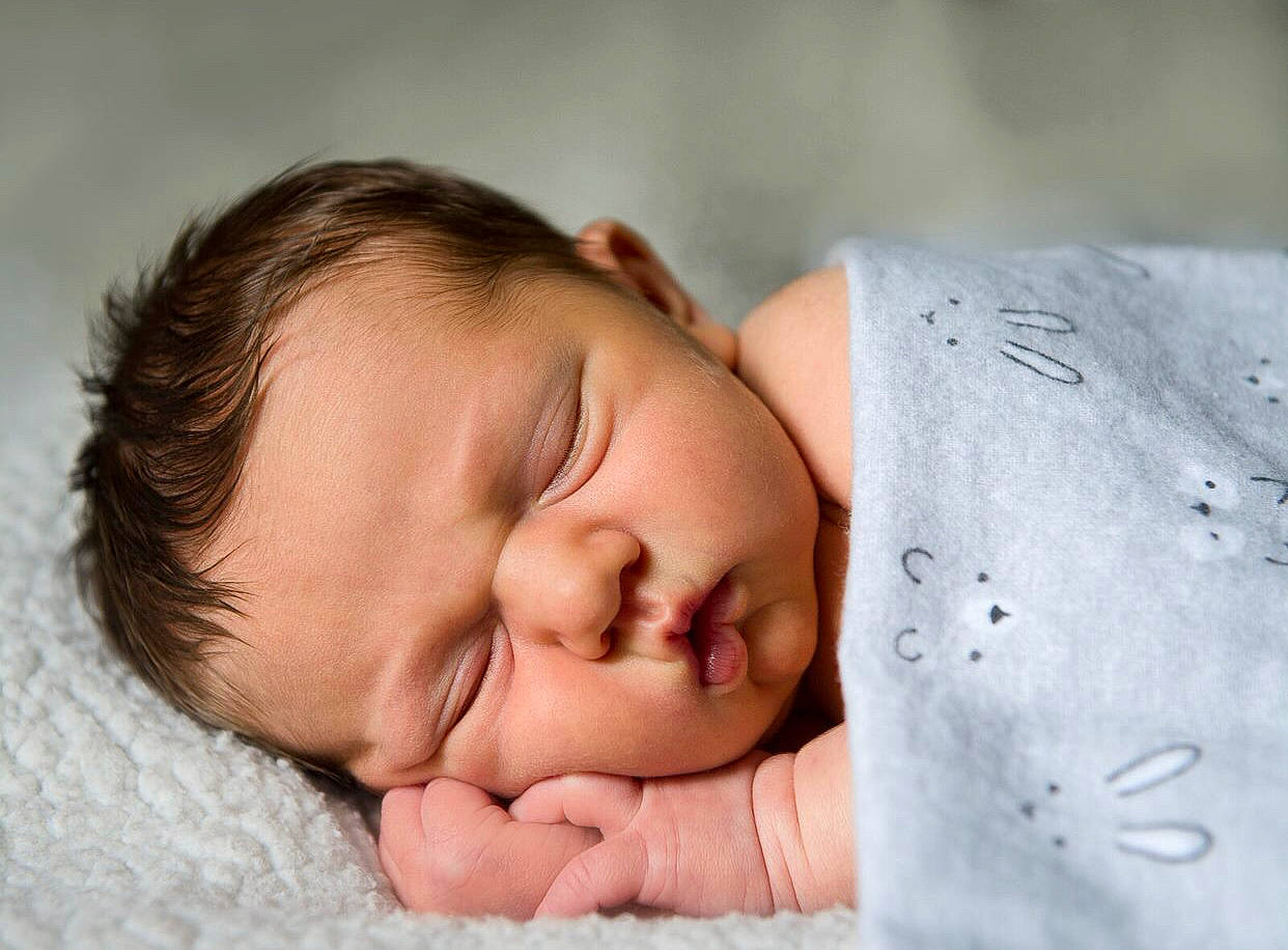 Samson is registered to the contest to win money with this photo: arm, baby, baby_toddler_clothing, bedtime, cheek, child, close_up, comfort, eyelash, facial_expression, grass, hand, happy, linens, nose, person, portrait_photography, skin, sleeve, smile