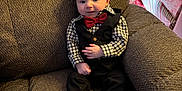 Brody is registered to the contest to win money with this photo: armchair, baby, bow_tie, brown_furniture, child, christmas, cozy, cute, festive, gift_wrap, holiday_decor, holiday_presents, indoor, infant, portrait, seated, smile, socks, tuxedo, young_child