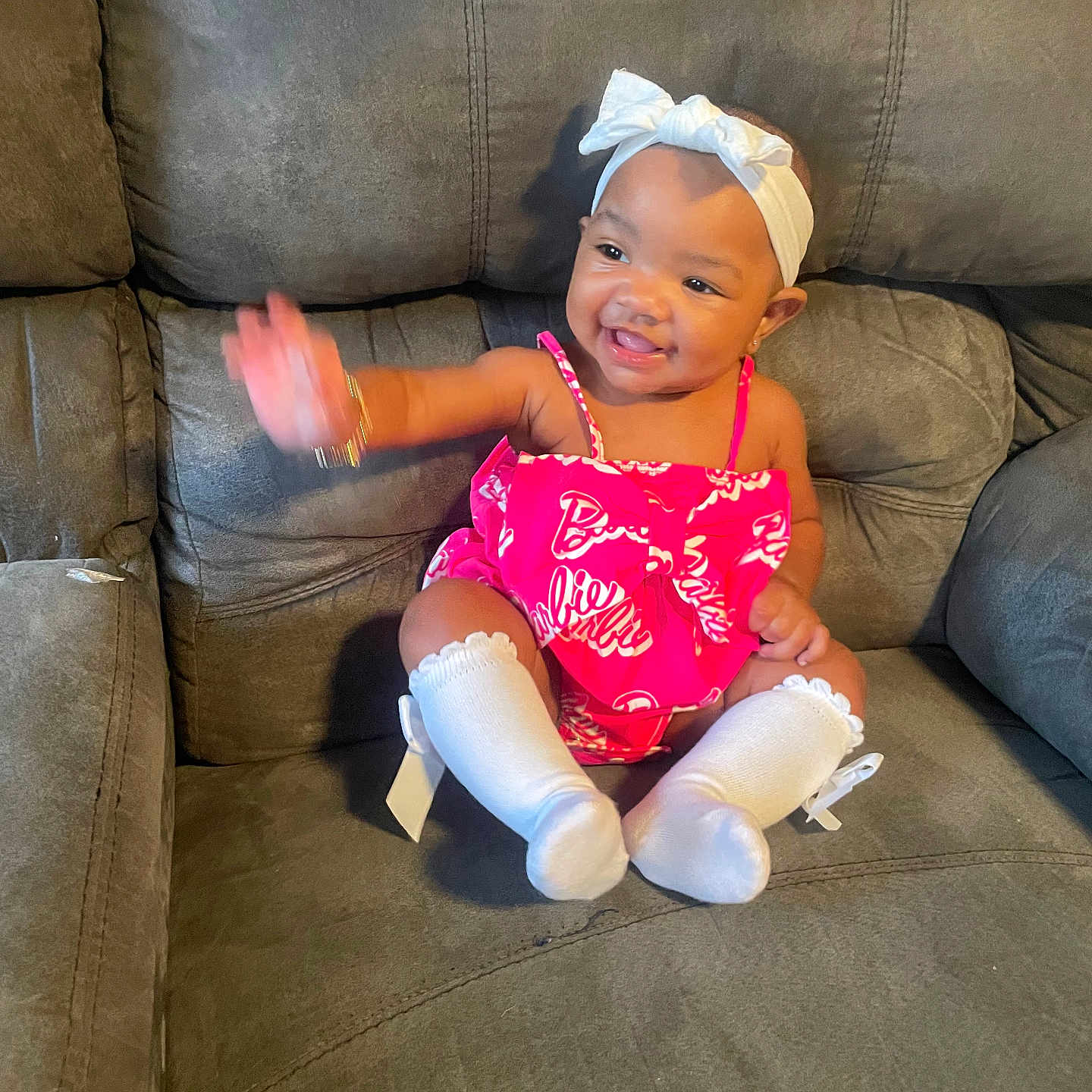 Malani joined the competition — help win amazing prizes! accessory, baby, casual, child, couch, cute, fashion, furniture, happy, headband, indoor, infant, joyful, person, pink_outfit, portrait, sitting, smiling, waving, white_socks