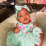 Malani joined the competition — help win amazing prizes! baby, child, girl, dress, headband, bow, cushion, indoor, bedroom, clothing, fabric, soft, smiling, person, infant, cute, sitting, skin, face, room