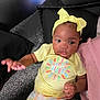 baby, child, yellow_shirt, headband, pillow, patterned_pants, indoor, cute, infant, person, portrait, colorful_clothing, relaxing, hand, face, expression, comfort, soft_surface, young_child, lying_down