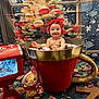 baby, child, red_headband, giant_mug, marshmallows, lollipop, christmas_tree, holiday, gingerbread_plush, red_mailbox, festive, smiling, indoors, decorations, winter, snowflakes, cute, playful, celebration, background