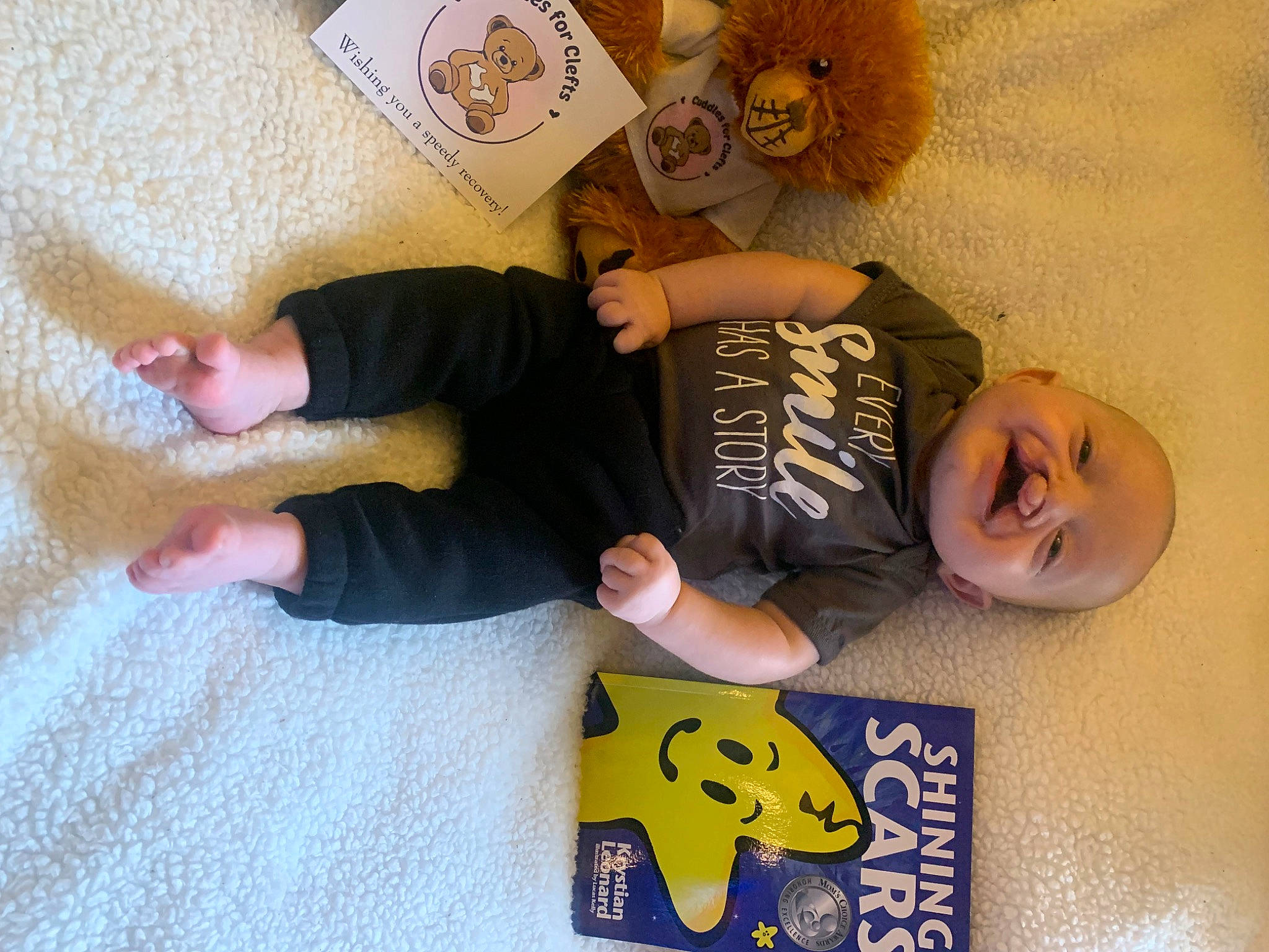 Noah is registered to the contest to win money with this photo: baby, baby_toddler_clothing, child, comfort, finger, flooring, font, foot, gesture, happy, mammal, person, room, sleeve, smile, t_shirt, thumb, toddler, wood, wrist