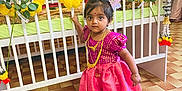 Alexia a rejoint le concours — aidez-le/la à gagner de superbes lots ! celebration, child, crib, curious, decor, dress, floor_tiles, flower_garland, furniture, gold_necklace, hair_accessory, indoor, jewelry, person, portrait, room, standing, toddler, traditional_clothing, young_girl