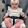 baby, child, stroller, pink_headband, flower_accessory, blue_eyes, cream_lace_outfit, knee_high_socks, tulle_flower, curious_expression, outdoor, infant, cute, soft_texture, sitting, baby_clothing, closeup, portrait, small_hands, baby_face