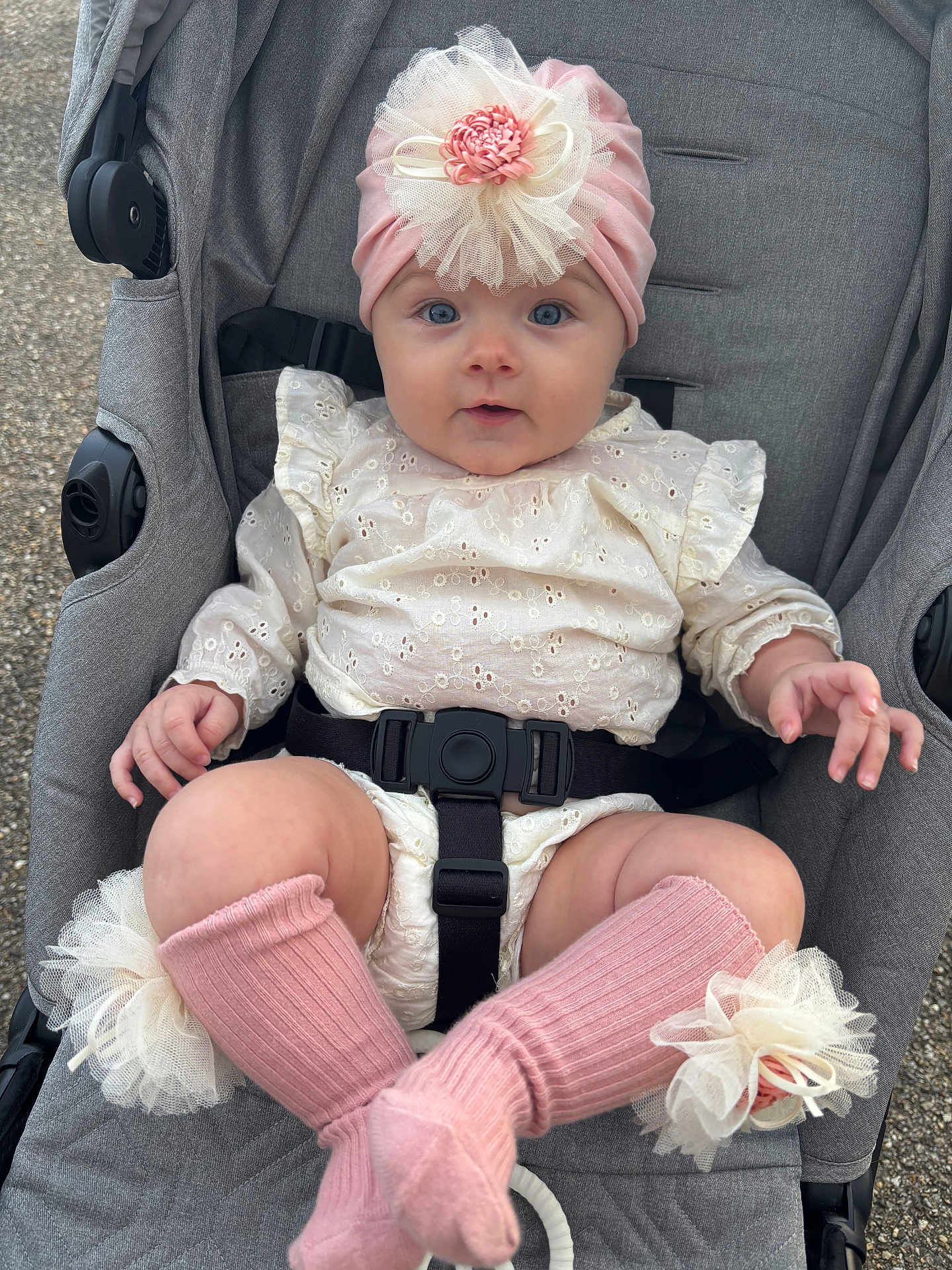 Joy Tribolet participe au concours pour gagner de l'argent avec cette photo : baby, child, stroller, pink_headband, flower_accessory, blue_eyes, cream_lace_outfit, knee_high_socks, tulle_flower, curious_expression, outdoor, infant, cute, soft_texture, sitting, baby_clothing, closeup, portrait, small_hands, baby_face