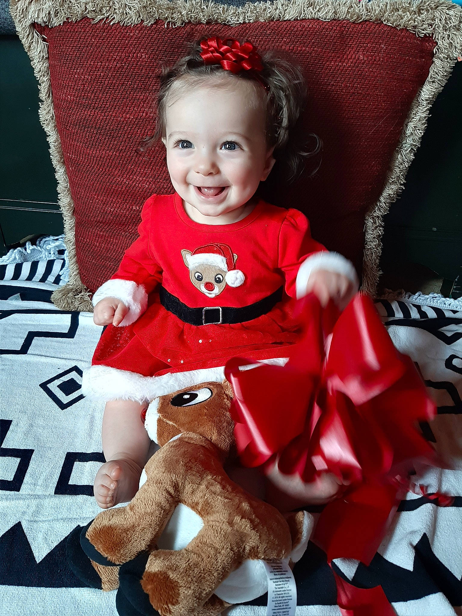 Allura is registered to the contest to win money with this photo: baby, child, christmas, christmas_eve, joy, person, red, sitting, toddler, toy