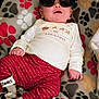 baby, sunglasses, blanket, paw_prints, red_pants, christmas_shirt, infant, cozy, cute, sleep_socks, lying_down, indoors, festive, clothing, child, portrait, relaxed, home, fashion, funny