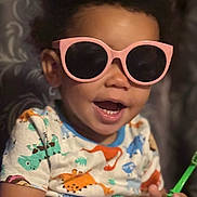 Nova joined the competition — help win amazing prizes! casual, child, colorful_clothing, cute, dinosaur_shirt, face, funny, hand, happy, holding_object, indoor, person, pink_sunglasses, playful, portrait, short_hair, smiling, sunglasses, toddler, young_child