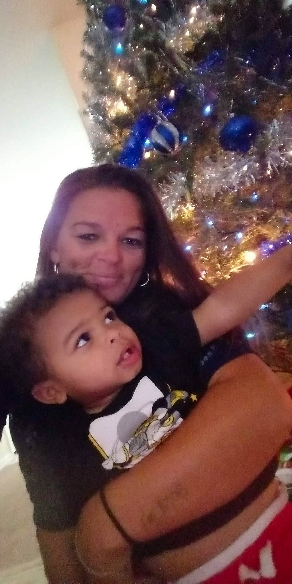 Malachi is registered to the contest to win money with this photo: black_hair, christmas, christmas_decoration, christmas_eve, christmas_ornament, christmas_tree, event, fun, happy, holiday, holiday_ornament, interior_design, joy, lap, leisure, long_hair, ornament, person, sitting, smile