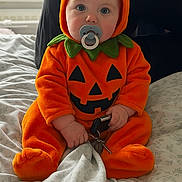 Hugo joined the competition — help win amazing prizes! baby, bed, blanket, child, costume, cute, face, footed_pajamas, green, halloween, hands, holiday, indoor, infant, keys, orange, pacifier, portrait, pumpkin_costume, sitting