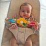 baby, infant, bouncer, toy, flower_toy, butterfly_toy, babybjorn, child, cute, indoor, soft_lighting, seated, clothing, hands, face, expression, furniture, floor, curious, comfortable