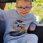 Ylliano a rejoint le concours — aidez-le/la à gagner de superbes lots ! child, glasses, sweatshirt, gray_clothing, sitting, chair, outdoor, greenery, smiling, casual, footwear, playful_text, young_boy, comfort, daylight, portrait, relaxed, woven_chair, fashion, happy