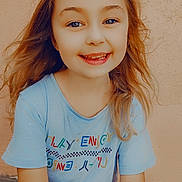 Yllana participe au concours pour gagner de l'argent avec cette photo : child, smiling, happy, tshirt, long_hair, blond, face, portrait, outdoor, casual_clothing, young, person, sitting, light_skin, wall, texture, colorful, bright, daylight, cute