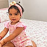 Caroline is registered to the contest to win money with this photo: child, toddler, girl, portrait, smiling, sitting, bedroom, bed, floral, pink_clothing, headband, curly_hair, earrings, baby, indoors, home, face, fashion, happy, photography