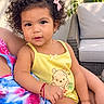 Caroline is registered to the contest to win money with this photo: toddler, child, baby, portrait, curly_hair, smiling, yellow_outfit, dress, bow, earring, outdoor, patio, flowers, pink_flowers, adult, lap, chair, cushion, sunlight, winnie_the_pooh