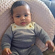 Arthur is registered to the contest to win money with this photo: baby, child, infant, portrait, sitting, indoors, couch, pillow, blanket, knitwear, gray_clothing, yellow_collar, face, eyes, hair, hands, cute, serious_expression, home, furniture